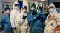 Sekelompok perawat dengan alat pelindung diri berpose sebelum shift malam mereka di rumah sakit Cremona, tenggara Milan, Lombardy pada 13 Maret 2020. Para pekerja kesehatan Italia kelelahan setelah selama bermingu-minggu berada di garda terdepan memerangi pandemi virus corona. (Paolo MIRANDA/AFP)