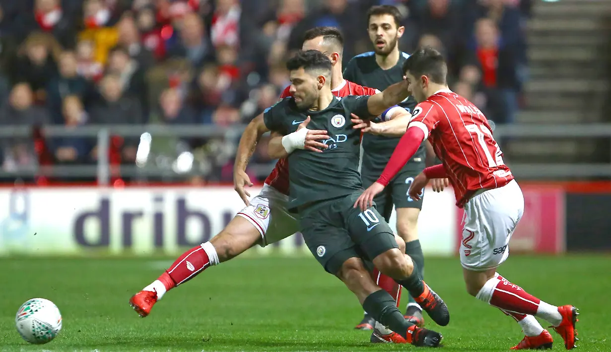 Pemain Manchester City, Sergio Aguero (tengah) mencoba keluar dari tekanan para pemain Bristol City pada semifinal Piala Liga Inggris di Ashton Gate stadium, Bristol,(23/1/2018). Manchester City menang 3-2. (AFP/Geoff Caddick)
