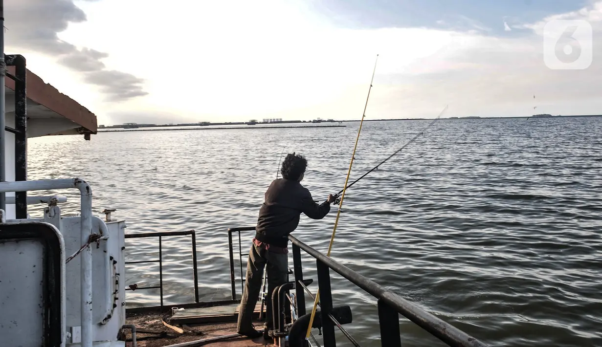 Warga memancing di atas sebuah kapal karam di pesisir Kali Adem, Muara Angke, Jakarta, Minggu (27/12/2020). Sebuah kapal yang telah karam selama bertahun-tahun tersebut dimanfaatkan oleh warga sebagai tempat memancing meskipun berisiko membahayakan keselamatan. (merdeka.com/Iqbal Nugroho)