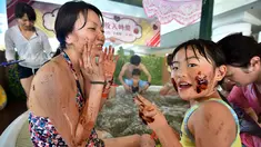 Seorang wanita dan putrinya menempelkan cokelat ke wajah mereka saat mandi spa cokelat di Hakone, Jepang, Senin (13/2). Mandi spa cokelat diadakan dalam rangka menyambut Hari Valentine. (AFP PHOTO / Kazuhiro Nogi)