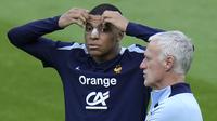 Pemain Prancis, Kylian Mbappe (kiri) di samping pelatih Didier Deschamps saat berlatih jelang laga Grup D melawan Belanda di Home Deluxe Arena Stadium, Paderborn, Jerman, Rabu (19/06/2024) waktu setempat. Mbappe terlihat menggunakan perban hidung setelah mengalami cedera patah tulang hidung pada laga Grup D Prancis melawan Austria Selasa (18/06/2024) WIB lalu. (AP Photo/Hassan Ammar)