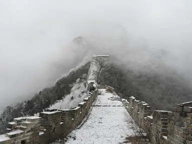 Tembok Besar China terlihat setelah hujan salju ringan di Jiankou, utara Beijing pada Minggu (9/1/2022). Jalur pada Tembok Besar China itu pun terlihat memutih akibat salju. (GREG BAKER / AFP)