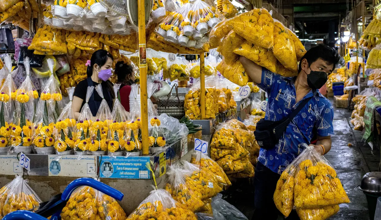 Seorang pria membawa bunga marigold menjelang Loy Krathong di pasar bunga Pak Khlong Talat, Bangkok, Kamis (18/11/2021). Bulan November ini Thailand akan mengadakan festival Loy Krathong di mana warga akan menghanyutkan keranjang berisi bunga dan lilin di sungai, kolam atau danau. (Jack TAYLOR/AFP)