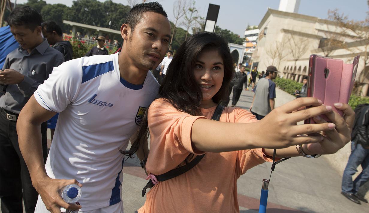 Kapten Persib, Atep berselfie dengan seorang fans usai latihan di Alun-alun Kota Bandung, Jawa Barat, Kamis (10/9/2015). (Bola.com/Vitalis Yogi Trisna)