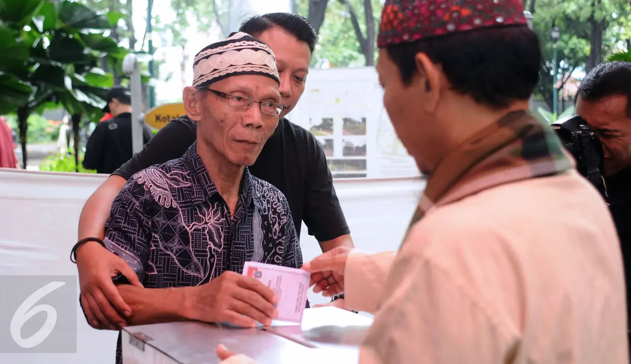 Petugas KPPS mengantar penyandang disabilitas memasukkan surat suara dalam simulasi pemungutan dan penghitungan suara Pilkada DKI Jakarta di Taman Menteng, Sabtu (28/1). Simulasi ini dilaksanakan oleh KPUD Jakarta Pusat. (Liputan6.com/Helmi Fithriansyah)
