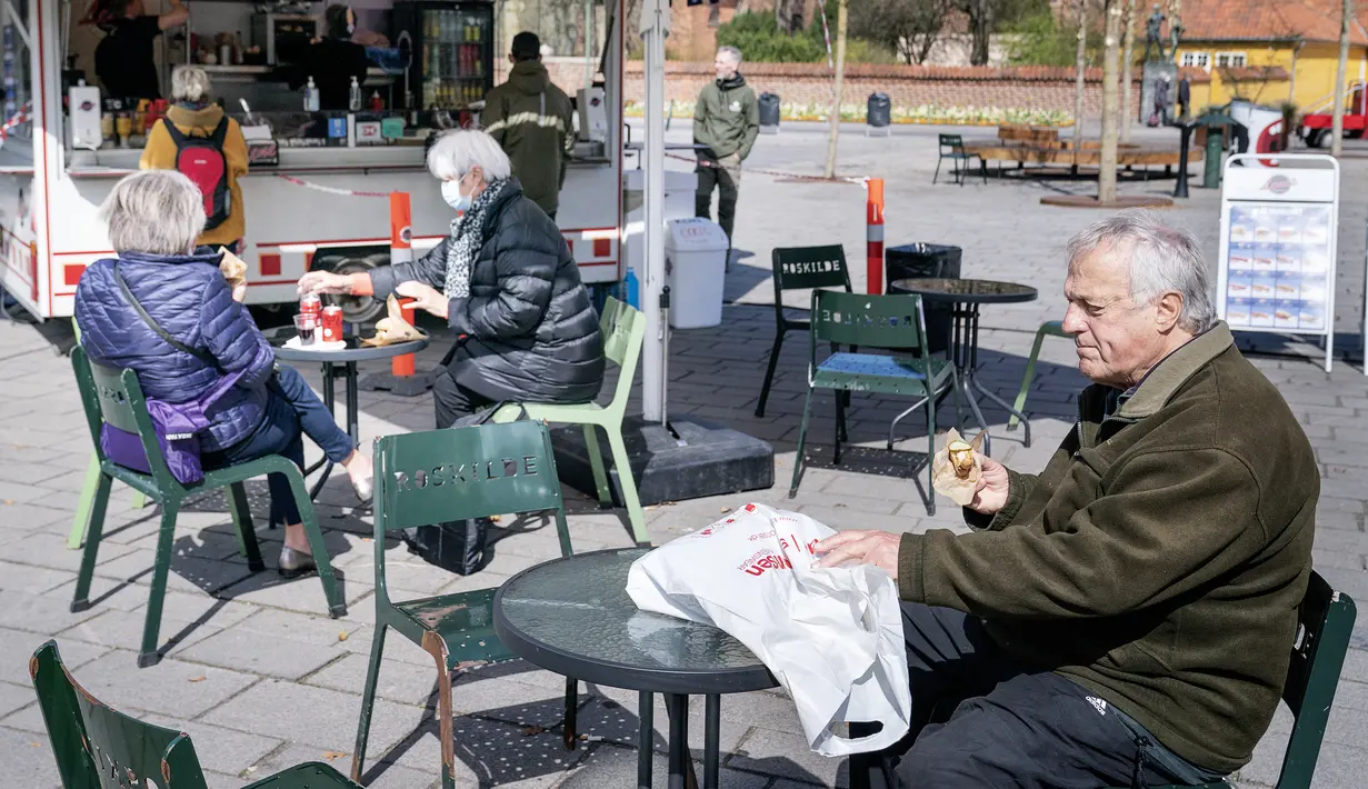 Orang-orang duduk menikmati layanan luar ruangan kafe di Roskilde Denmark, saat kafe dan bar dibuka kembali pada Rabu (21/4/2021). Denmark membuka kembali berbagai aktivitas ekonomi negaranya setelah kasus infeksi Covid-19 mengalami penurunan. (Claus Bech/Ritzau Scanpix via AP)