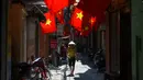 Warga berjalan di sepanjang gang yang dihiasi bendera nasional Vietnam menjelang perayaan Hari Nasional Vietnam di Hanoi (1/9/2020). Peringatan 75 tahun Hari Nasional Vietnam jatuh pada tanggal 2 September 2020. (AFP Photo/Nhac Nguyen)