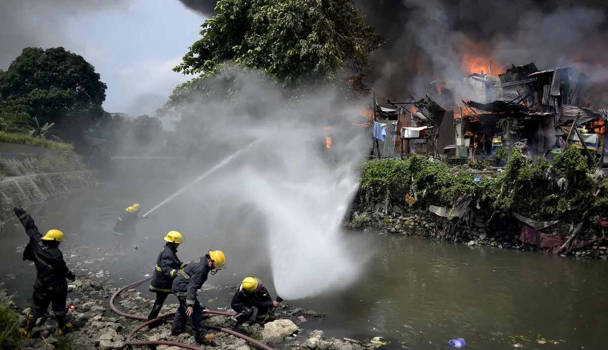 Petugas pemadam kebakaran mengambil air dari sungai untuk memadamkan api yang membakar kawasan kumuh di Manila, Filipina (11/8). (AFP Photo/Noel Celis)
