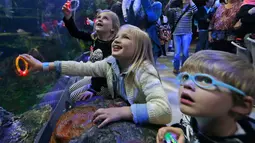Ekspresi anak-anak saat menyaksikan atraksi putri duyung di Virginia Aquarium di Virginia Beach (3/4). Aquarium ini menyajikan atraksi putri duyung setiap minggunya selama bulan April. (AP Photo/Steve Helber)