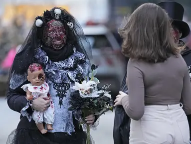 Orang-orang yang mengenakan kostum menakutkan tiba di pusat kota untuk Zombie Walk dan Parade Halloween tahunan di Essen, Jerman, Minggu (31/10/2021). Setiap 31 Oktober sebagian masyarakat dunia ikut memeriahkan perayaan Halloween. (AP Photo/Martin Meissner)