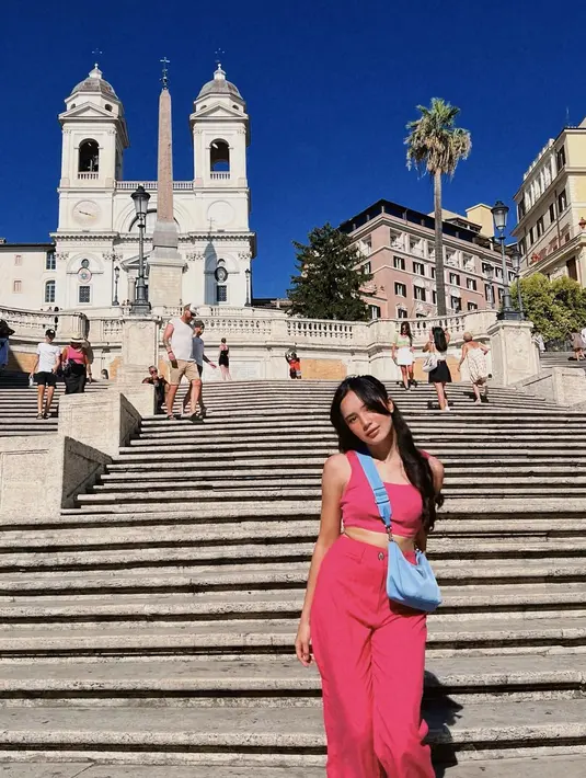 Beby Tsabina saat berpose Spanish Steps, Roma. Ia tampil cantik dengan busana serba pink sambil membawa tas serta sepatu warna putih. (Instagram/bebytsabin)