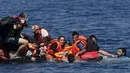 Pengungsi Suriah berusaha menyelamatkan diri saat perahu karet mereka bocor sekitar 100 m sebelum mencapai pulau Lesbon, Yunani, Minggu (13/09/2015). Total 432.761 pengungsi melakukan perjalanan berbahaya menuju Eropa. (REUTERS/Alkis Konstantinidis)