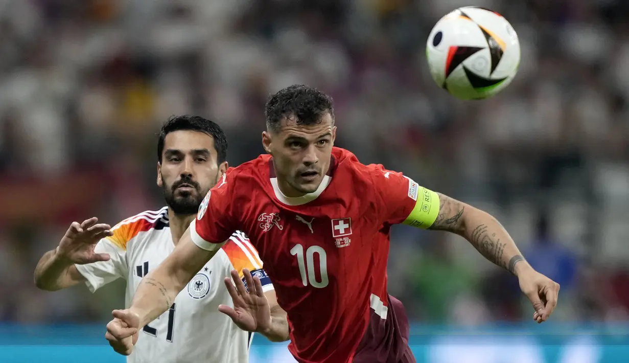 Kapten Timnas Swiss, Granit Xhaka menghalau bola di depan gelandang Timnas Jerman, Ilkay Gundogan pada laga matchday ketiga Grup A Euro 2024 di Waldstadion, Frankfurt, Jerman, Minggu (23/6/2024). (AP Photo/Martin Meissner)