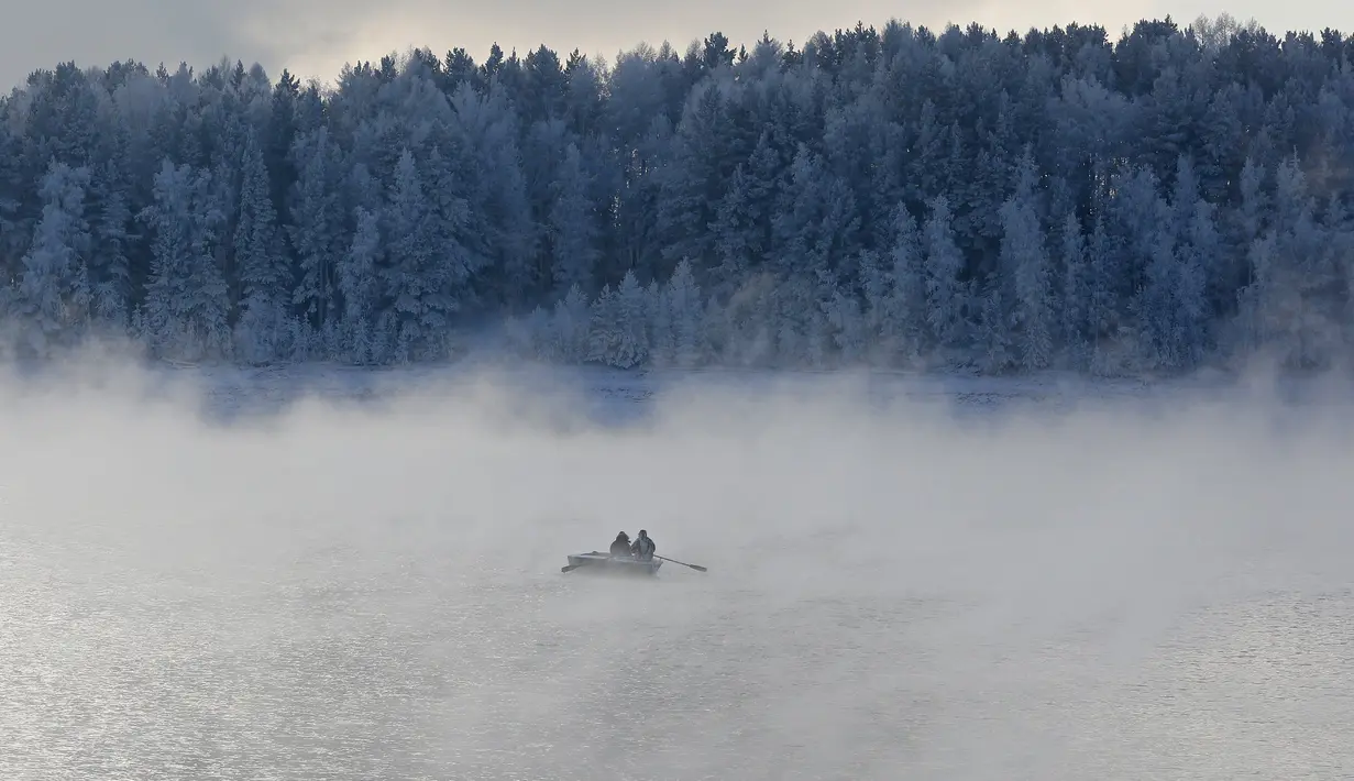 Tampak dua orang mendayung perahu di sepanjang Sungai Yenisei ditengah kabut dingin di Taiga luar kota Siberia Krasnoyarsk, Rusia, Selasa (17/11/2015). Suhu udara minus hingga 20 derajat Celsius. (REUTERS/Ilya Naymushin)
