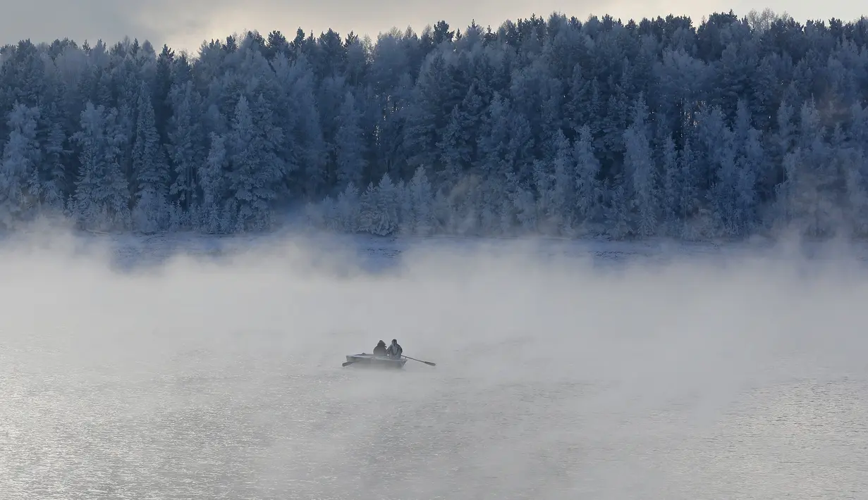 Tampak dua orang mendayung perahu di sepanjang Sungai Yenisei ditengah kabut dingin di Taiga luar kota Siberia Krasnoyarsk, Rusia, Selasa (17/11/2015). Suhu udara minus hingga 20 derajat Celsius. (REUTERS/Ilya Naymushin)
