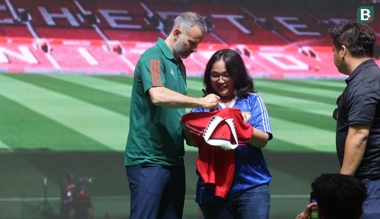 Legenda Manchester United, Ryan Giggs membubuhkan tanda tangannya di atas jersey seorang fans saat sesi meet and greet dalam acara peluncuran kartu kredit Maybank yang berkolaborasi dengan Manchester United di Jakarta Convention Center (JCC), Senayan, Jakarta, Sabtu (18/5/2024). (Bola.com/M Iqbal Ichsan)