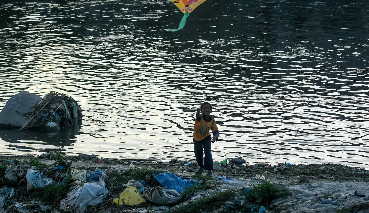 Seorang anak menerbangkan layang-layang di tepi sungai menjelang festival Hindu Dashain di Kathmandu (7/10/2020). Festival ini yang paling dinantikan di Nepal, Bhutan, Burma, dan perbukitan India Utara. (AFP/Prakash Mathema)