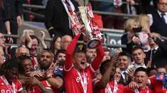 Bek Nottingham Forest, Joe Worrall mengangkat trofi usai mengalahkan Huddersfield Town pada final playoff divisi Championship di Stadion Wembley di London, Senin (30/5/2022). Nottingham Forest menang tipis atas Huddersfield Town 1-0. (AFP/Adrian Dennis)