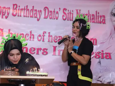 Siti Nurhaliza meniup lilin disaksikan Krisdayanti saat perayaan ulang tahun sang Diva asal Malaysia di restoran cepat saji kawasan Kemang, Jakarta, Minggu (10/1). Pelantun tembang Cindai ini berulang tahun pada 11 Januari. (Liputan6.com/Herman Zakharia)
