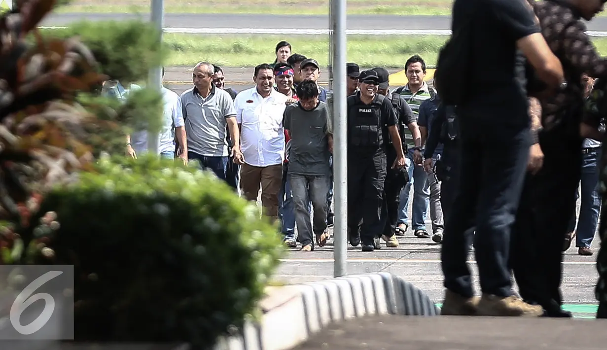Tersangka Ridwan Sitorus tertunduk saat tiba di Bandara Halim Perdana Kusuma, Jakarta, Minggu (1/1).  Sebelumnya, Ridwan Sitorus alias Pius Pane ditangkap di Pool Bus di Medan, Sumatera Utara sekitar pukul 07.45 WIB. (Liputan6.com/Faizal Fanani)