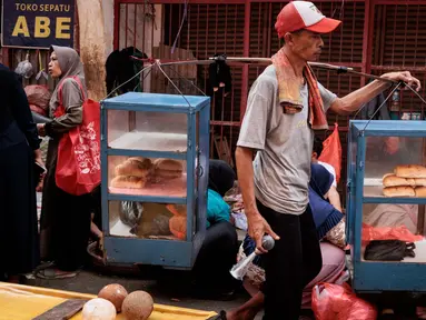 Seorang pedagang makanan kaki lima berjalan di sebuah pasar, Bogor, Jawa Barat pada 13 Februari 2025. (Yasuyoshi CHIBA/AFP)