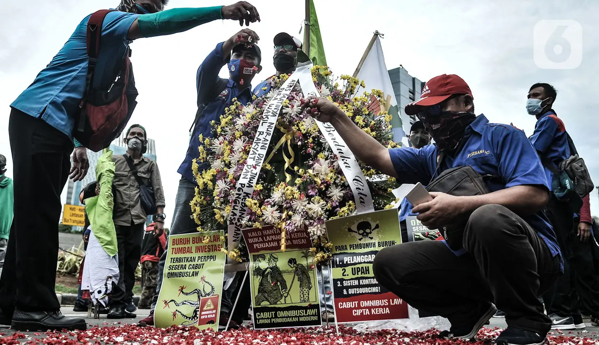 Massa buruh menaburkan bunga sebagai simbol duka atas kebijakan pemerintah di kawasan Patung Kuda, Jakarta, Senin (2/11/2020). Buruh dari berbagai serikat pekerja menggelar demo terkait penolakan pengesahan omnibus law Undang-Undang Cipta Kerja dan upah minimum 2021. (merdeka.com/Iqbal S Nugroho)