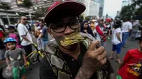 Seorang pria memperlihatkan seekor ular saat momen Car Free Day (CFD) di kawasan Bundaran HI, Jakarta, Minggu (29/1). Tak sedikit pengunjung CFD yang ingin berfoto dengan hewan reptil tersebut. (Liputan6.com/Faizal Fanani)