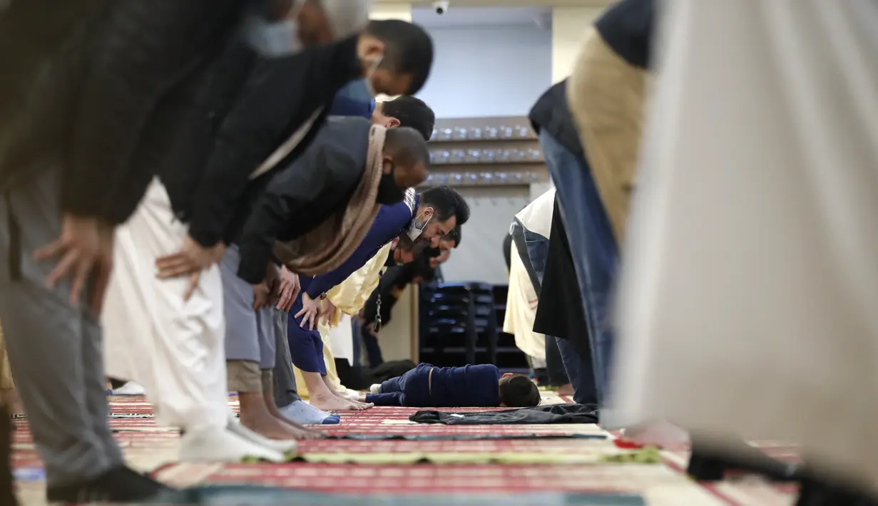 Seorang anak berbaring saat umat Muslim melaksanakan sholat tarawih dengan menerapkan jarak sosial pada malam pertama bulan suci Ramadhan di Pusat Komunitas Muslim Chicago, Senin (13/4/2021). (AP Photo/Shafkat Anowar)