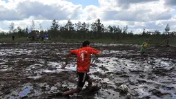 Seorang peserta dari Rusia menendang bola diatas lumpur pada ajang Rusia Swamp Football Cup di Saint Petersburg, (9/7/2016). (AFP/STR)