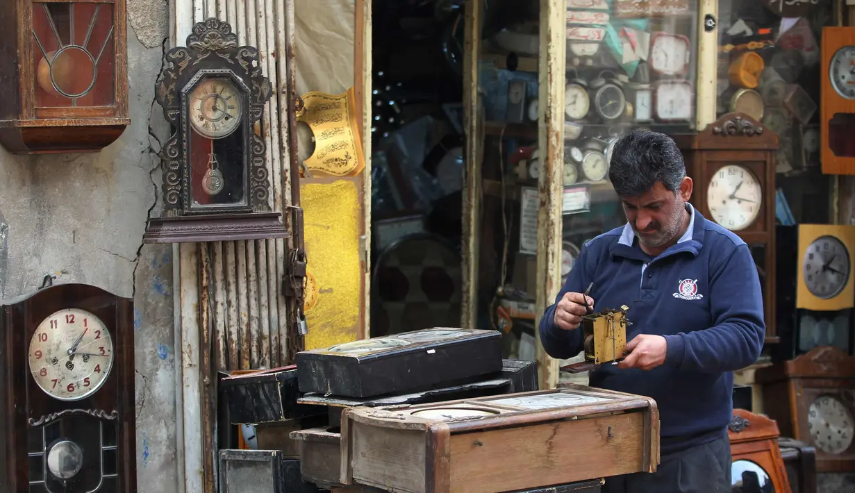 Hussein Mahmud (45) mengecek kerusakan jam antik di gudangnya di daerah Maidan Baghdad (20/2). Mahmud mengumpulkan jam kuno berumur 60 sampai 150  tahun lalu dari pelelangan dan penjual jalanan. (AFP Photo/Ahmad Al-Rubaye)