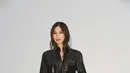 Gemma Chan tampil edgy dengan setelan jumpsuit kulit hitam bergaya militer lengkap dengan sabuk kulit, tas selempang hitam, dan ankle boots hitam. [dok. Burberry]