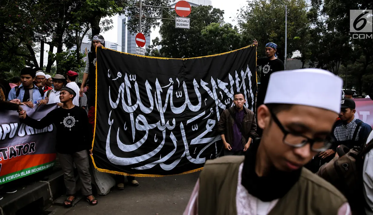 Peserta aksi membentangkan bendera saat menggelar unjuk rasa di Pintu Barat Monas, Jakarta, Selasa (18/7). (Liputan6.com/Faizal Fanani)