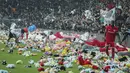 Pemain Besiktas dan Antalyaspor dibantu petugas mengumpulkan boneka yang dilemparkan oleh penonton pada laga lanjutan Liga Turki 2022/2023 yang berlangsung di Stadion Vodafone, Istanbul, Minggu (27/02/2023). Aksi tersebut ditujukan sebagai bentuk sumbangan untuk anak-anak korban gempa Turki. (AP Photo)