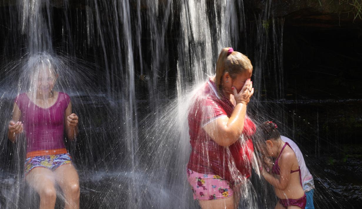 Orang-orang menyejukkan diri dari cuaca yang sangat terik di sungai saat gelombang panas di Paraguari, Paraguay, Minggu (16/1/2022). Suhu Paraguay secara umum mencapai 41 derajat celsius. (AP Photo/Jorge Saenz)