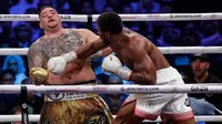 Petinju Andy Ruiz Jr (kiri) menghindar saat Anthony Joshua (kanan) melepaskan pukulan ke arahnya dalam kejuaraan tinju kelas berat dunia di Diriyah Arena, Riyadh, Arab Saudi, Minggu (8/12/2019). Anthony Joshua menang angka mutlak atas Andy Ruiz Jr. (AP Photo/Hassan Ammar)