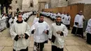 Diaken dan pendeta Katolik Roma berjalan saat prosesi perayaan Natal di Manger Square di luar Gereja Nativity di Kota Betlehem, Palestina, Minggu (24/12). (AFP/Musa Al Shaer)