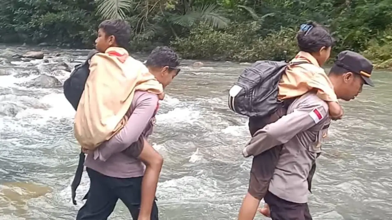 Anggota Polsek Kuwus, Kabupaten Manggarai Barat, NTT saat menggendong siswa nyebrang sungai ke sekolah