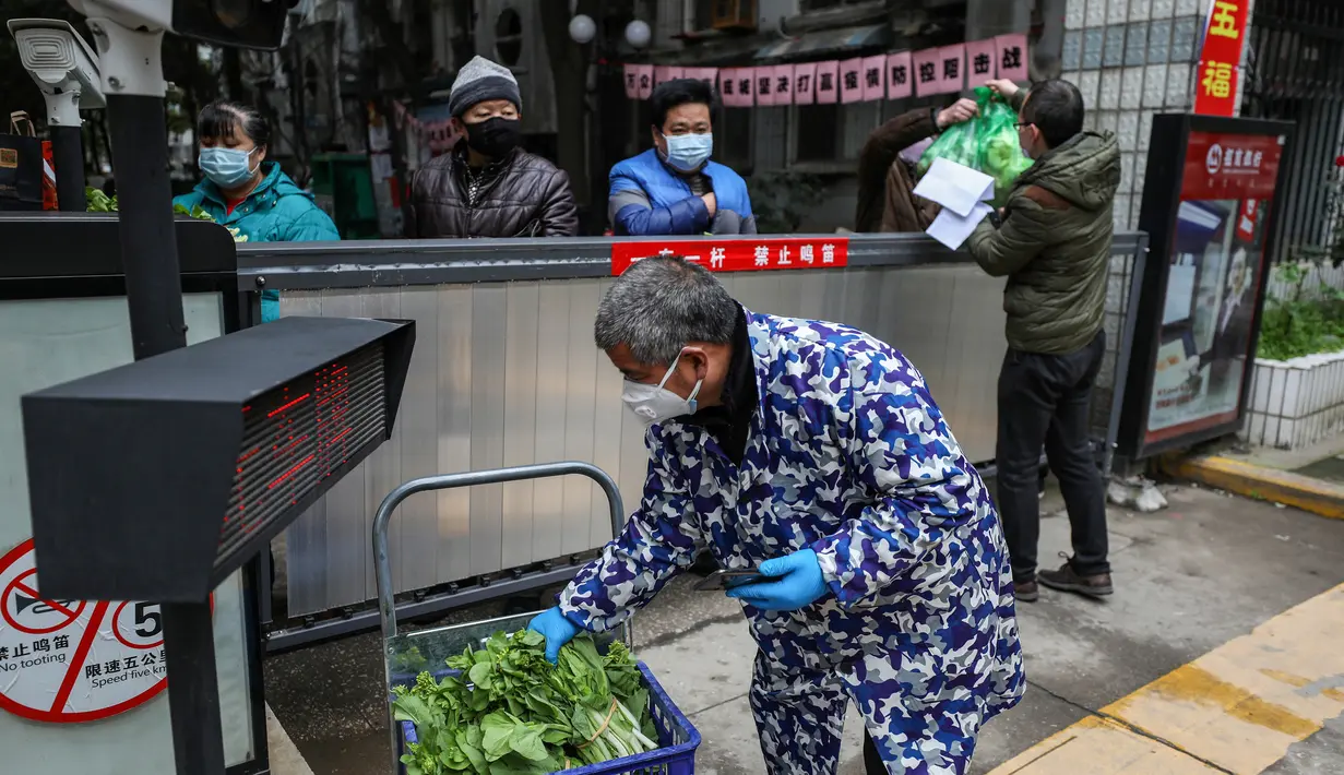 Seorang warga menerima sayuran di atas gerbang di Wuhan di provinsi Hubei tengah China (3/3/2020). Sejauh ini, total 80.026 kasus virus corona terkonfirmasi di wilayah China daratan. (AFP/STR)