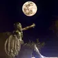 Penampakan super snow moon di antara Alexander the Great (kanan) dan Diogenes of Sinope (kiri) di Corinth, Yunani, 19 Februari 2019. (VALERIE GACHE / AFP)