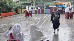 Seorang guru mengenakan sandal akibat sepatu rusak oleh banjir di SDN Bukit Duri 11, Jakarta, Senin (6/1/2020). Banjir menyebabkan sekitar 50 persen siswa SDN Bukit Duri 11 tidak masuk sekolah karena mayoritas tinggal di kawasan Kampung Melayu dan Kampung Pulo. (merdeka.com/Iqbal S. Nugroho)