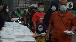 Warga menerima pembagian nasi bungkus gratis di Posko Perjuangan Rakyat (POSPERA), Jakarta, Rabu (10/3/2021). Pembagian 500 nasi bungkus beserta masker dan vitamin secara gratis setiap harinya dalam bentuk meringankan beban warga di tengah pandemi Covid-19. (merdeka.com/Imam Buhori)