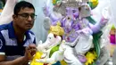 Seorang perajin mengerjakan pembuatan patung Dewa Ganesha di sebuah bengkel di Mumbai, India, 24 Agustus 2021. Pembuatan patung dewa Hindu berkepala gajah tersebut dilakukan jelang Festival Ganesh Chaturthi. (SUJIT JAISWAL/AFP)