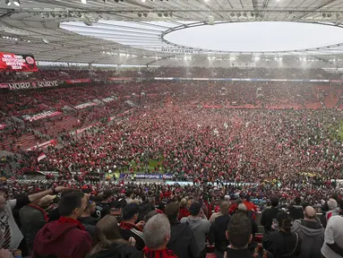 Suporter Bayer Leverkusen memadati lapangan pertandingan untuk merayakan keberhasilan timnya memastikan gelar juara Liga Jerman 2023/2024 setelah mengalahkan Werder Bremen di BayArena, Leverkusen, Jerman, Senin (15/04/2024) WIB. (AP Photo/DPA/David Inderlied)