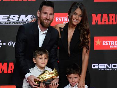 Pemain Barcelona, Lionel Messi didampingi istrinya Antonella Roccuzzo dan kedua putranya berpose setelah menerima trofi Sepatu Emas keenamnya selama acara penyerahan di Antiga Fabrica Estrella Damm, Barcelona, Spanyol (16/10/2019). (AFP Photo/Josep Lago)