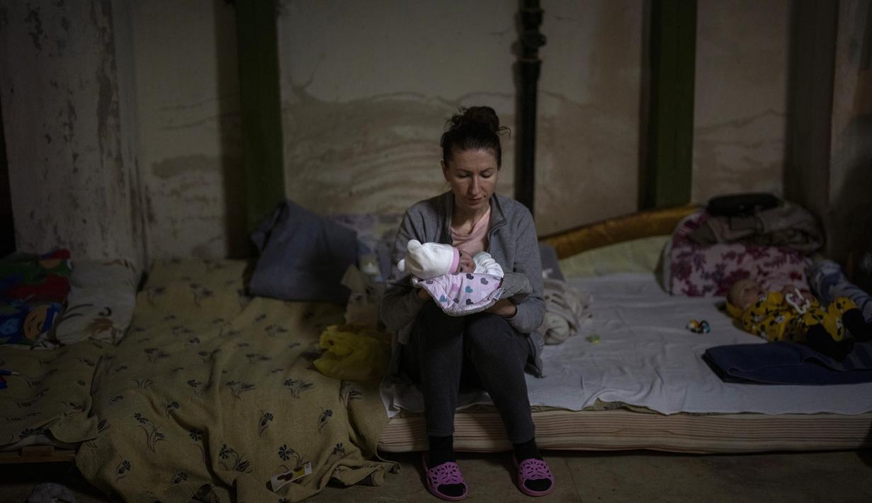 Seorang perempuan menggendong bayinya yang baru lahir di dalam ruang bawah tanah yang digunakan sebagai tempat perlindungan bom di rumah sakit anak Okhmadet di Kiev tengah, Ukraina, Senin (28/2/2022). Hingga kini invasi militer Rusia ke Ukraina terus berlanjut. (AP Photo/Emilio Morenatti)