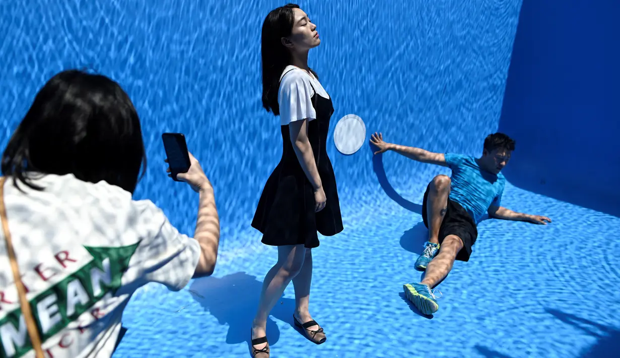 Pengunjung berfoto di karya seni Swimming Pool dalam sebuah pameran pameran bertajuk "The Confines of the Great Void" di Museum CAFA, Beijing, 23 Juli 2019. Karya seni unik itu pun banyak dikunjungi wisatawan yang ingin punya foto underwater keren tanpa harus basah-basahan. (WANG Zhao/AFP)