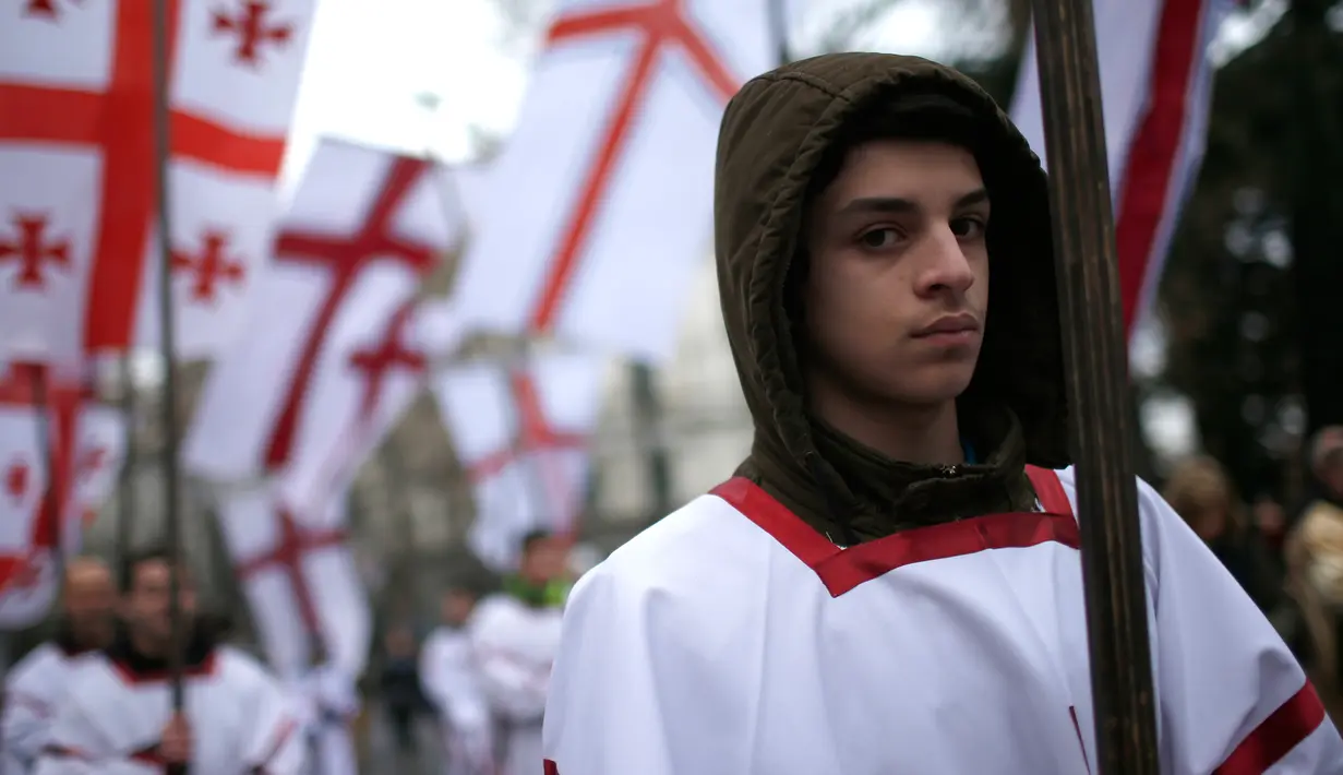 Peserta "Alilo" memegang bendera selama mengikuti pawai bersama di jalanan Tbilisi, Georgia, Kamis (7/1). Para peserta ini merupakan penganut Kristen Ortodoks di Georgia. (REUTERS/David Mdzinarishvili)