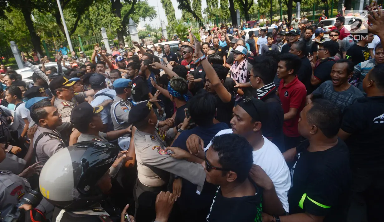 Massa driver taksi online yang tergabung dalam Aliando terlibat aksi saling dorong dengan polisi saat menggelar demo di Jalan Medan Merdeka Barat, Jakarta, Rabu (28/3). Dalam aksinya mereka sempat bersitegang dengan polisi. (Merdeka.com/Imam Buhori)