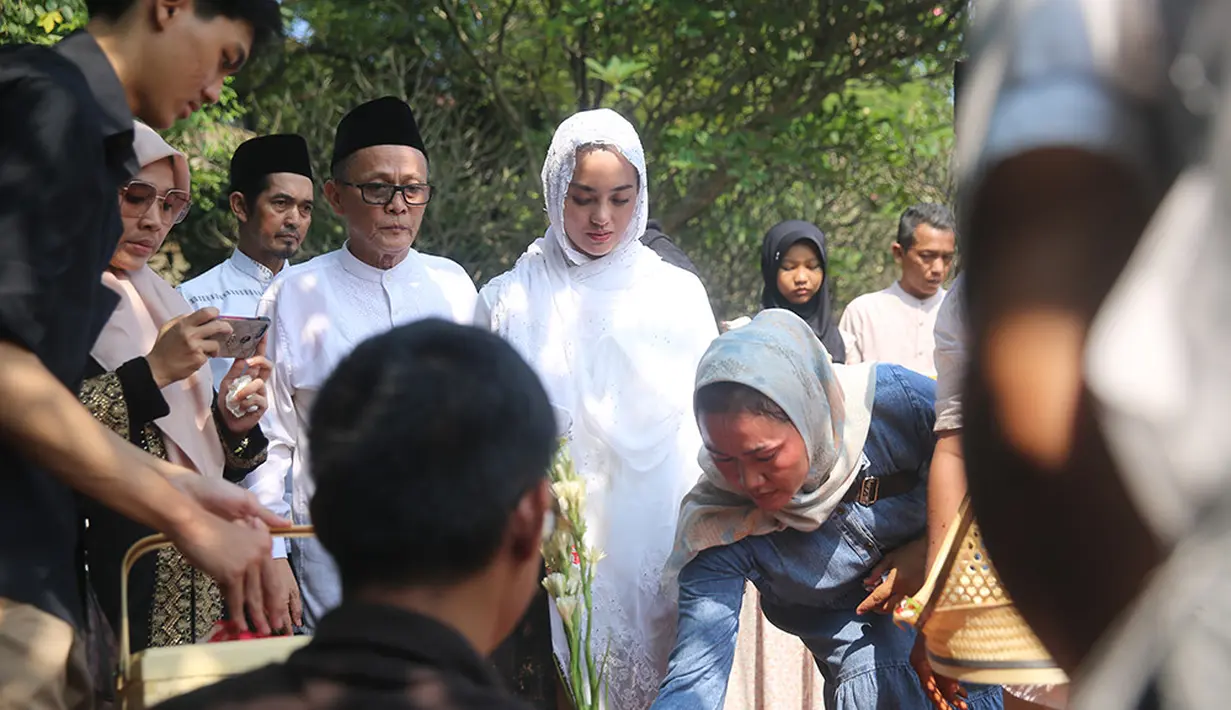 Sebelum dimakamkan, Ririn juga tampak selalu mendampingi sang suami yang dirumah duka. Ririn tampak mengusap punggung sang suami untuk  menguatkan yang menangis di samping jenazah sang ayah. [Foto; Adrian Putra/Fimela.com]