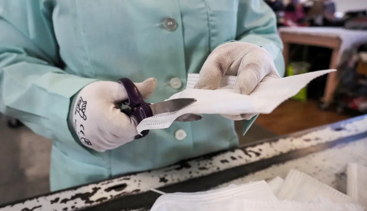 Pekerja perusahaan Audacie membersihkan masker bekas untuk perusahaan Plaxtil di Chatellerault, Prancis, 25 Agustus 2020. Startup di Prancis, Plaxtil, mendaur ulang masker dan plastik untuk dijadikan pelindung wajah, pembuka pintu, dan pengencang masker. (GUILLAUME SOUVANT/AFP)